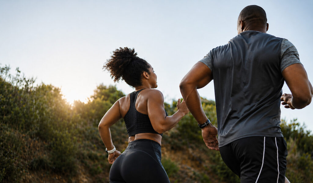 Couple running together on coastal trail, back view