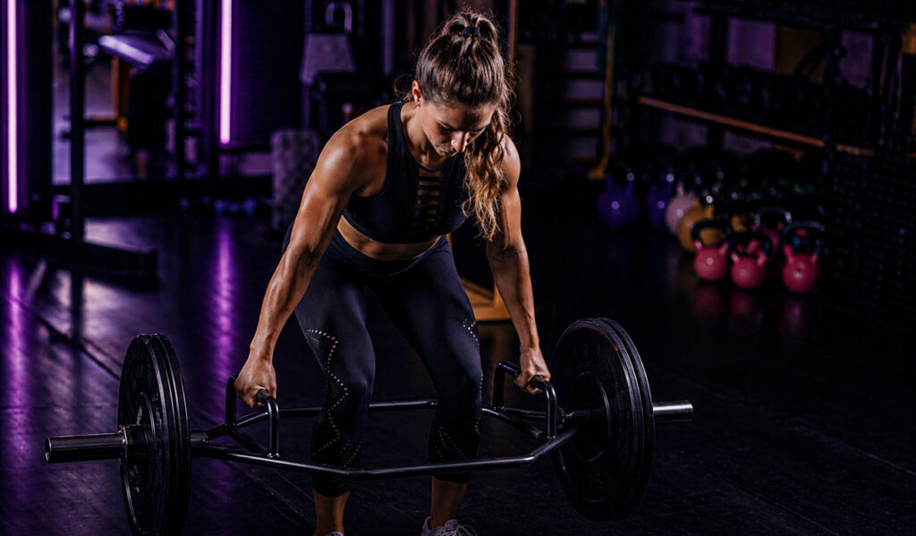 Woman weightlifting in dark gym, side view